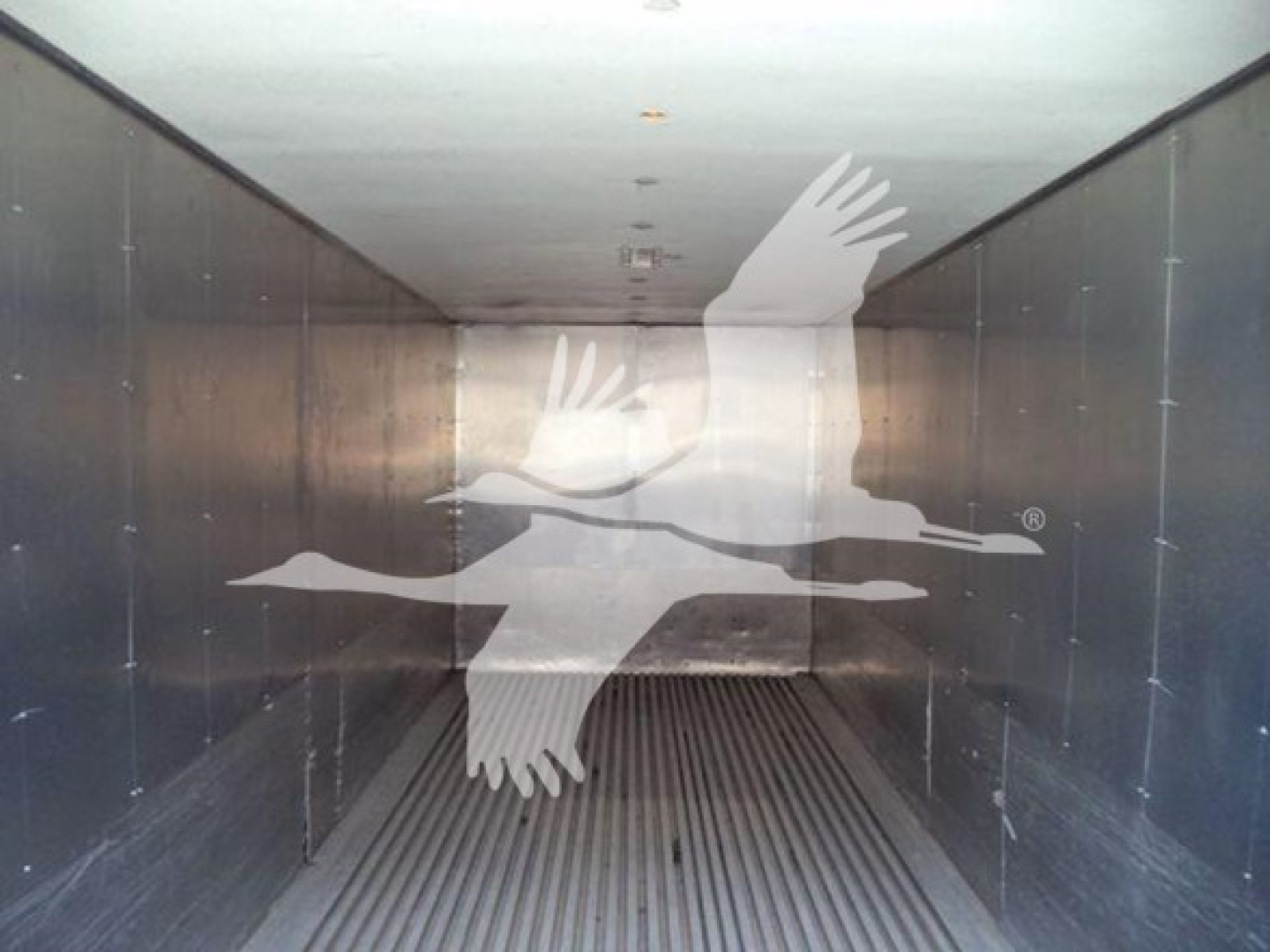 Truck interior view showing empty metal cargo area with ribbed floor; watermark of flying goose logo centered.