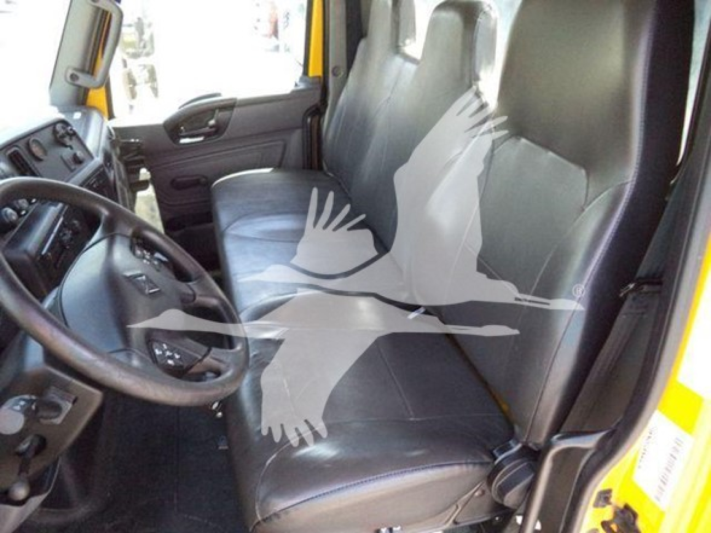 Interior of a 2020 International MV truck cab showing driver and passenger seats with black leatherette upholstery, steering wheel, and dashboard visible.