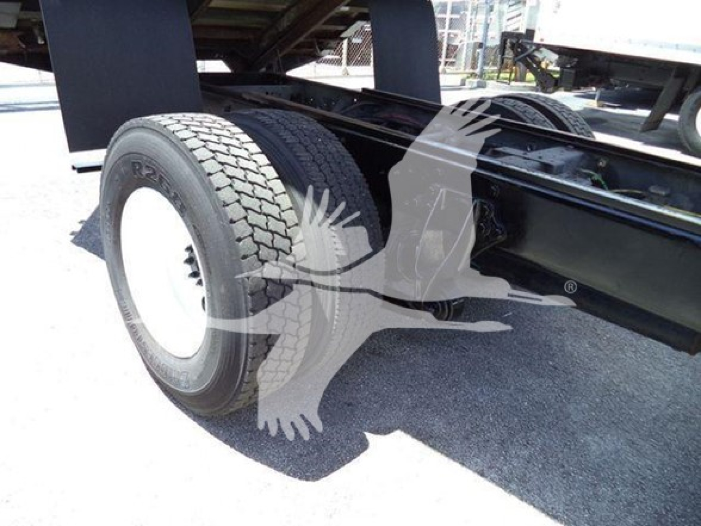 Truck chassis with rear dual axle and large tire, undercarriage visible, part of a green/black truck frame.