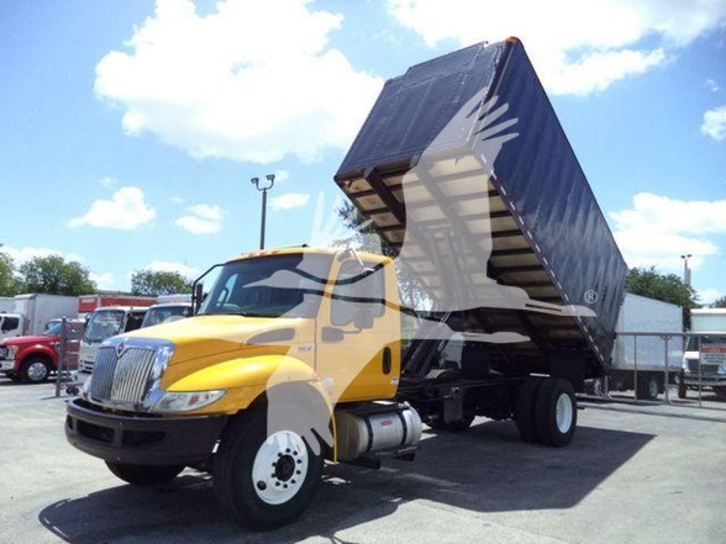 Truck cab and dump bed raised showing front left angle of 2020 International MV truck in yard.