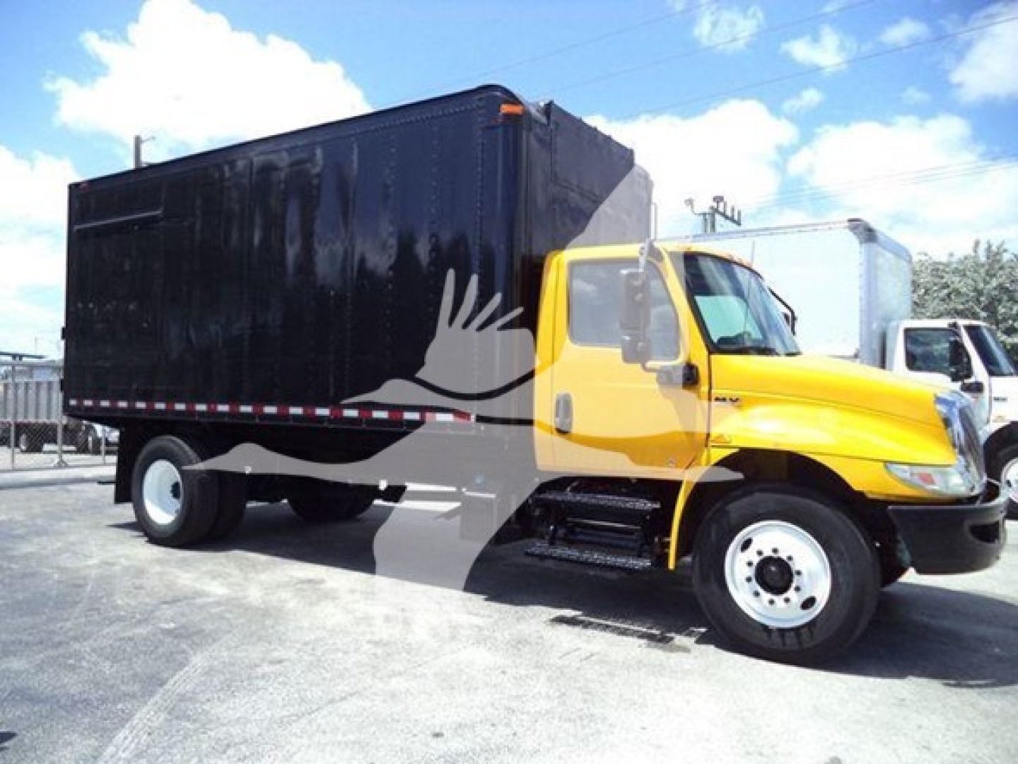 Truck chassis showing a yellow cab with a large black dump body, side view, 2020 International MV chassis cab with stock number T43630