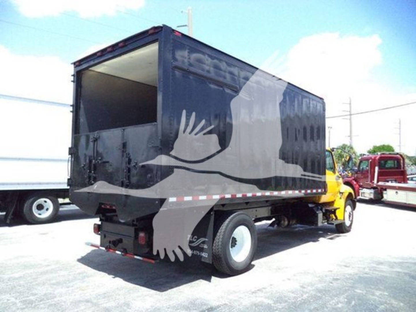 Truck chassis showing black dump body with white eagle graphics and side access doors.