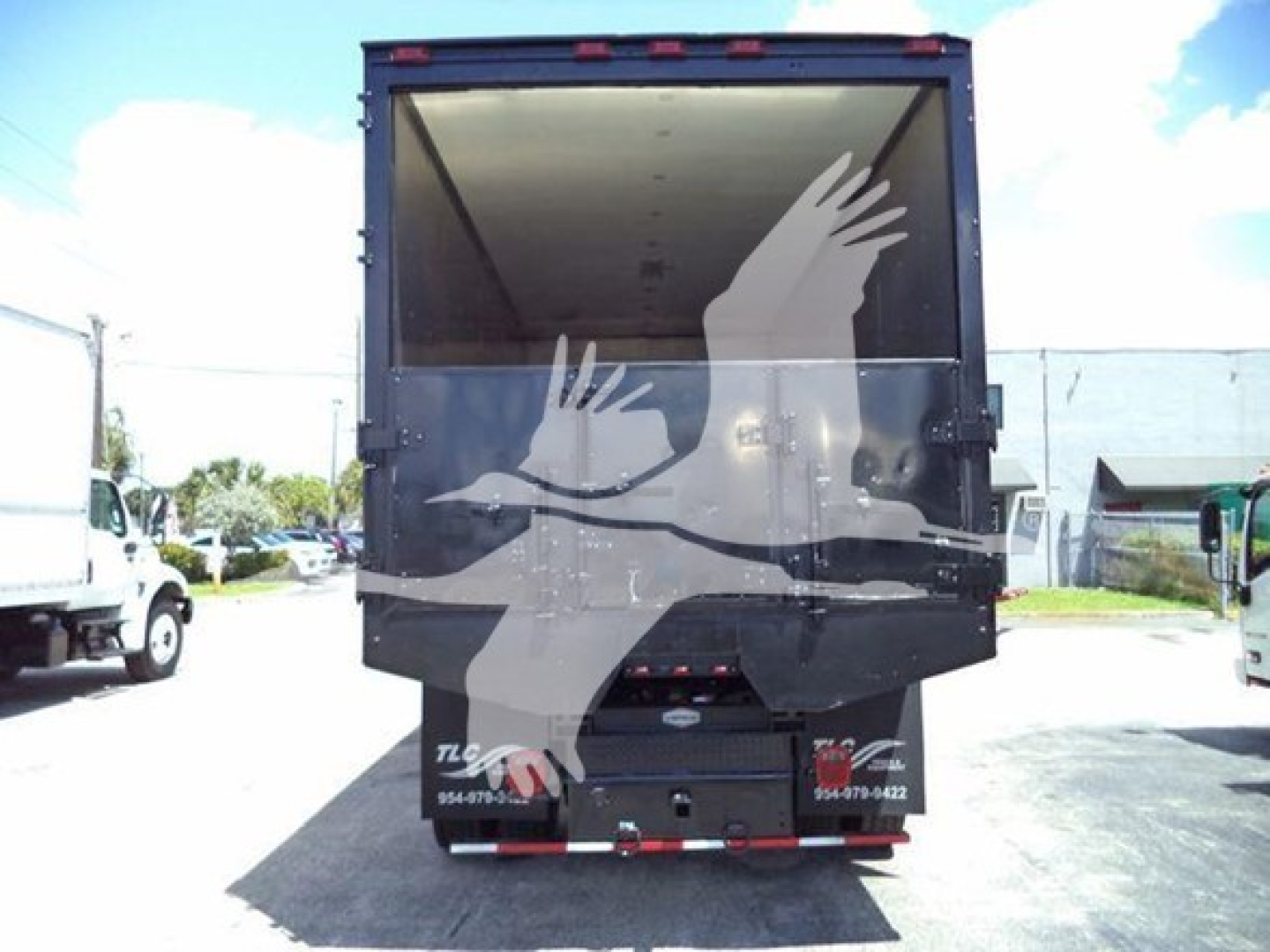 Truck rear showing container with white graphic birds on back, taillights, and bumper; open top cargo area.