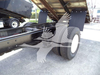 Chipper truck undercarriage showing dual rear axles and wheel with white rim; structural frame and hydraulic components visible.