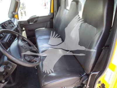 Interior of a 2020 International MV truck cab showing driver and passenger seats with black leatherette upholstery, steering wheel, and dashboard visible.
