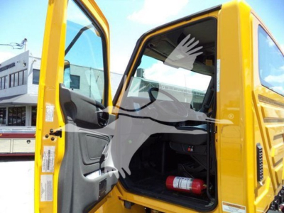 Cabin interior and door area of a yellow International MV truck with open door, showing driver seat and red fire extinguisher.