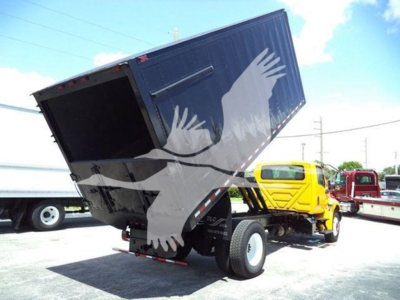 Dump bed truck showing raised black dump body on a yellow International MV chassis with stock number T43630 and VIN 3HAEUMMLXLL143630 visible.