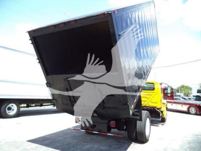 Truck bed in lifted up position showing empty container and wheel behind with cab visible in background.