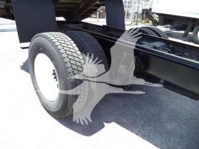Truck chassis with rear dual axle and large tire, undercarriage visible, part of a green/black truck frame.