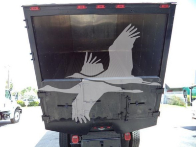 Truck dump bed rear view showing tailgate and hydraulic lines in service with a black finish.