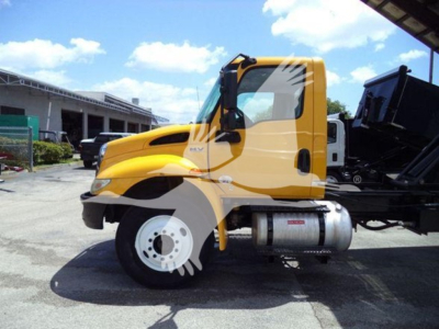 Wheel-lift truck side view showing yellow International MV cab and fuel tank, with stock number and VIN not visible.