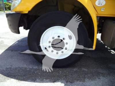 Wheel and front fender of a yellow 2020 International MV truck showing a large white wheel rim and tire with partial vehicle body in background