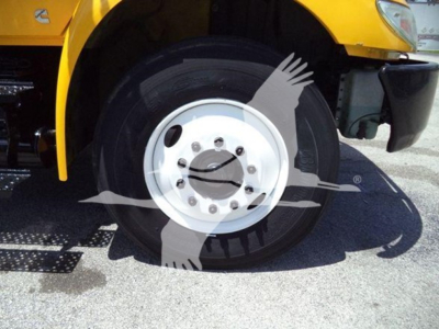 Wheel and tire close-up on a yellow International MV truck cab showing front axle and hub assembly