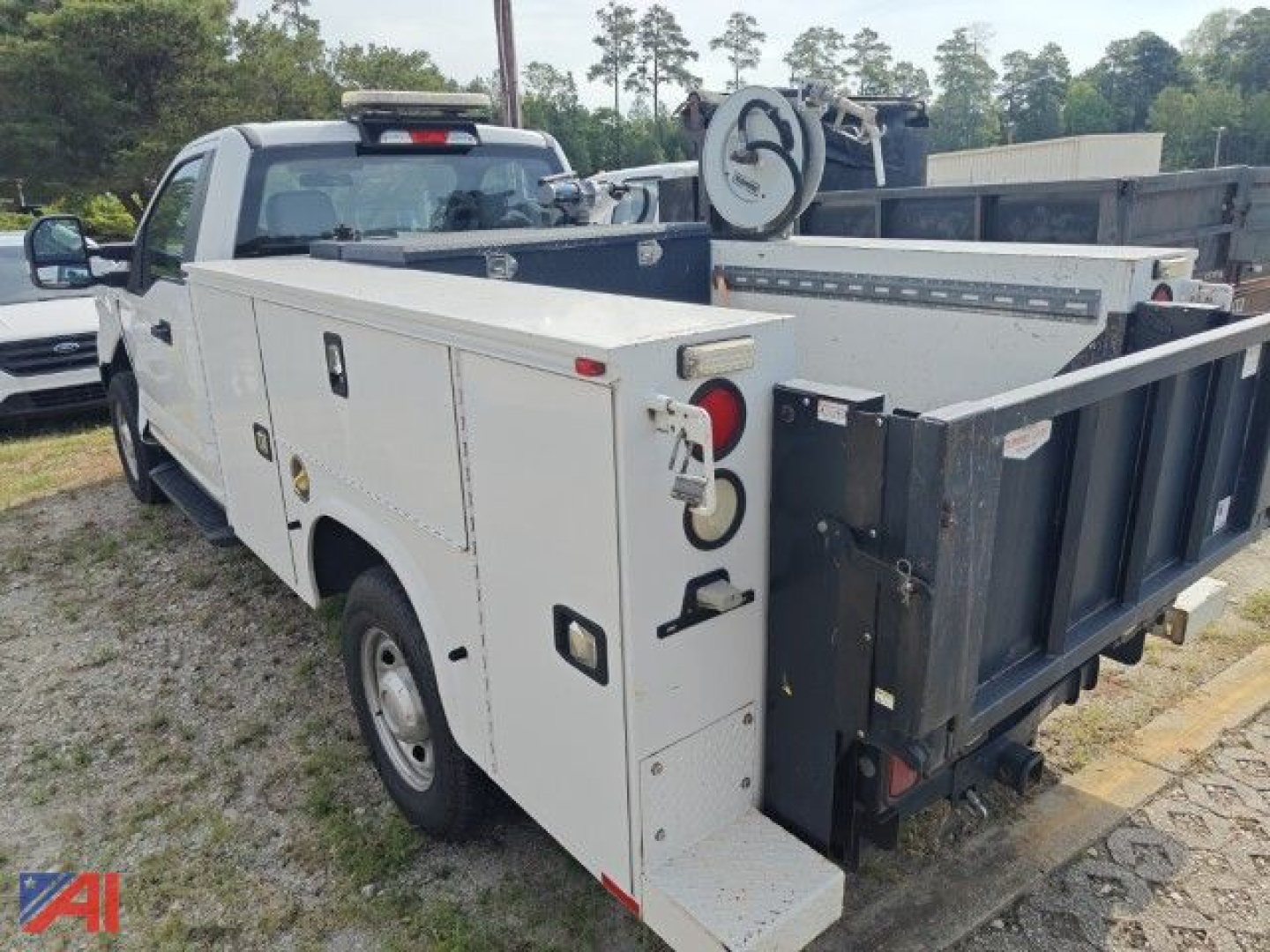 Utility service body truck with white cargo compartments and a black dump bed viewed from rear-left side.