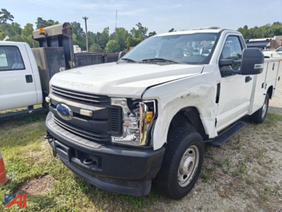 Ford F-250 Super Duty pickup truck with front-end damage, white cab, service utility body, 4x4, in a salvage yard.