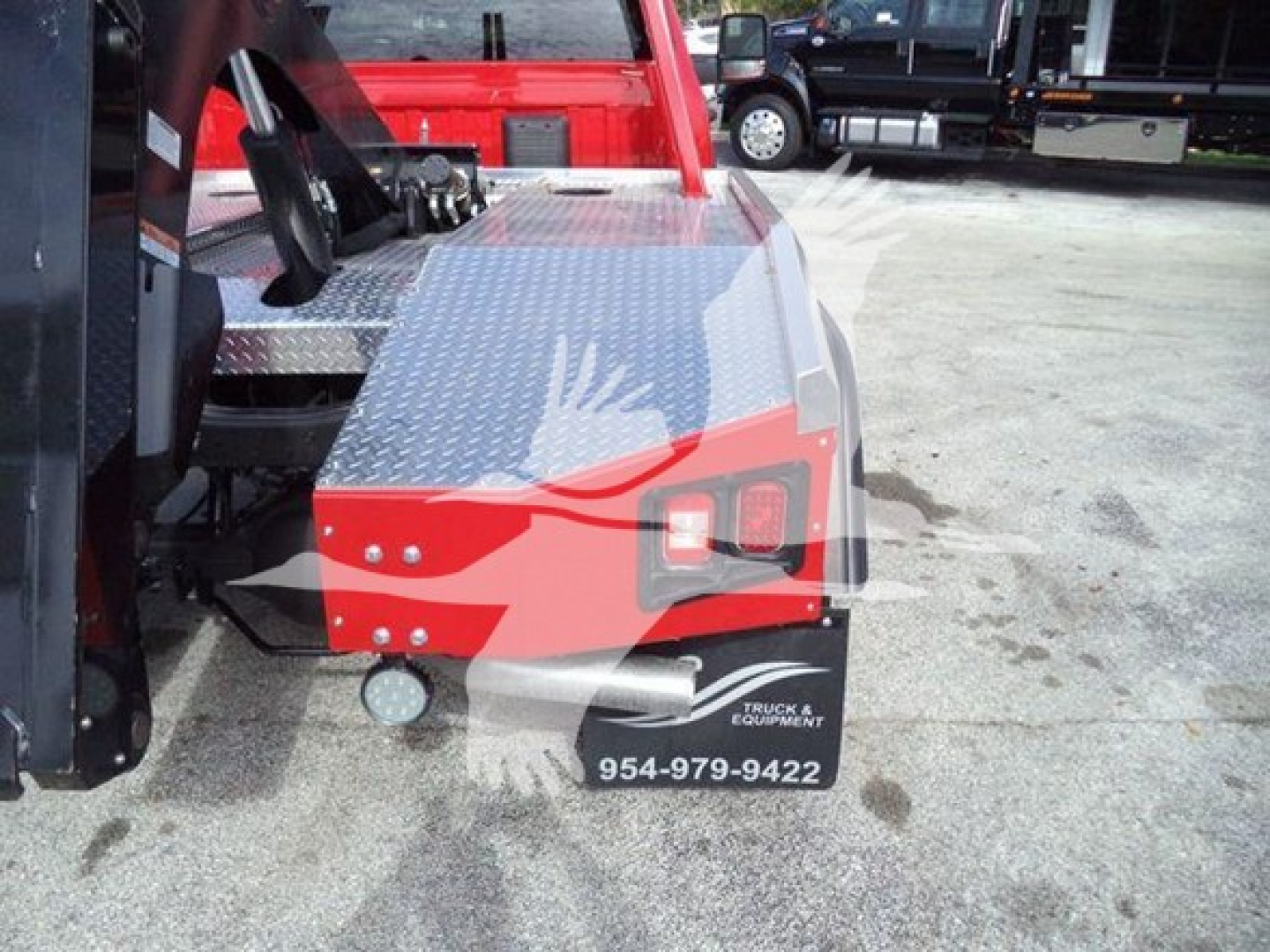 Ram 4500 truck rear/sidestep area showing diamond plate metal deck and taillight; includes black mudflap with white text and a phone number.