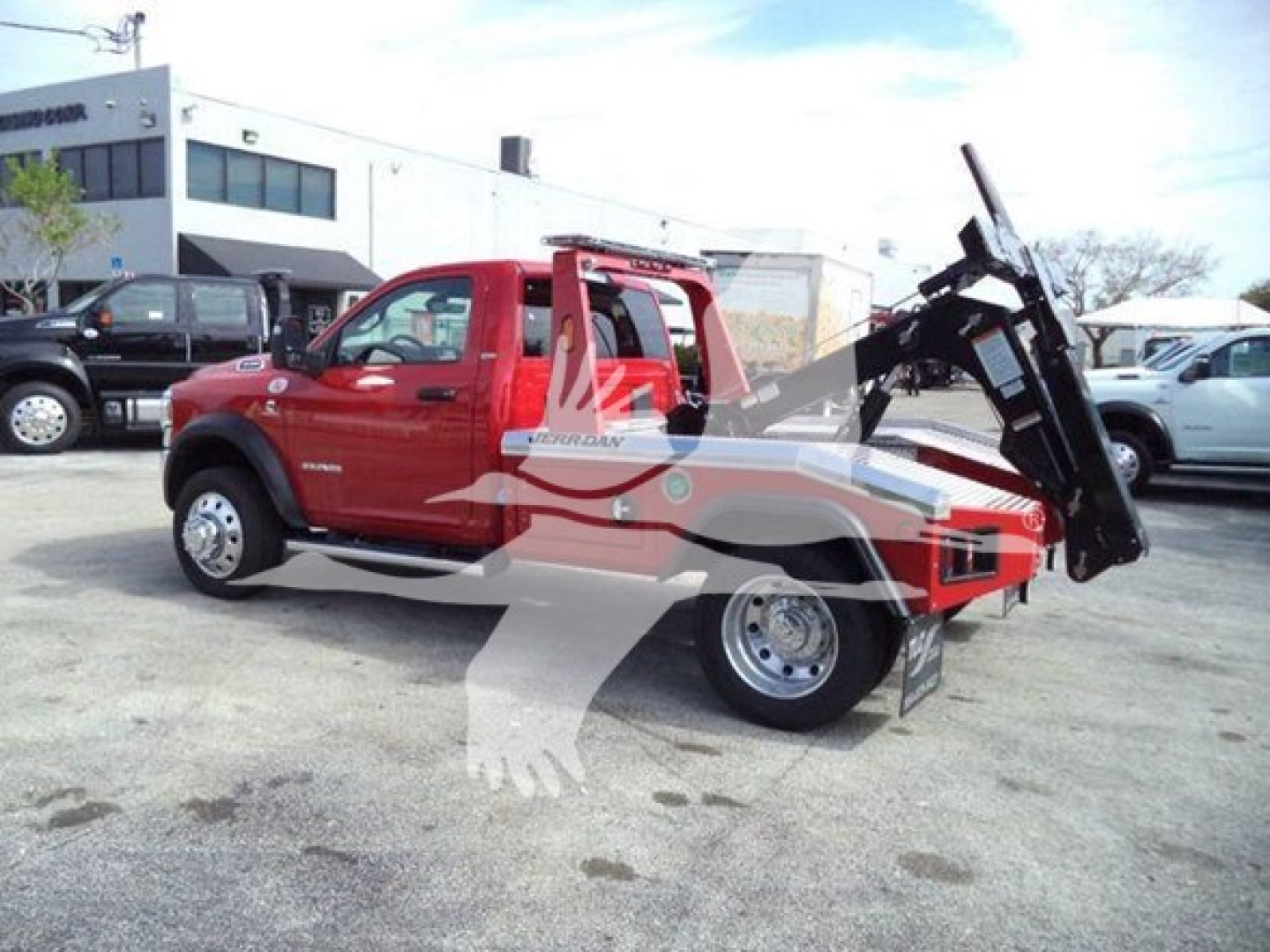 Ram 4500 SLT towing bed with hydraulic wheel-lift/wrecker attachment and crane in red color, parked at dealership lot with other vehicles in background.