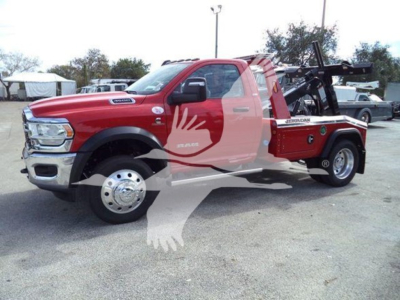 Ram 4500 tow truck front-left view showing red cab and winch-equipped flatbed with decals.