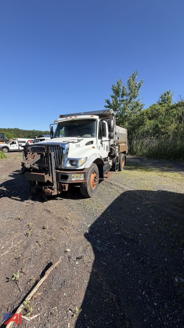 Dump truck 2004 International WorkStar 7400 in outdoor lot, white cab, dump bed, front grille guard, large tires, clear blue sky.