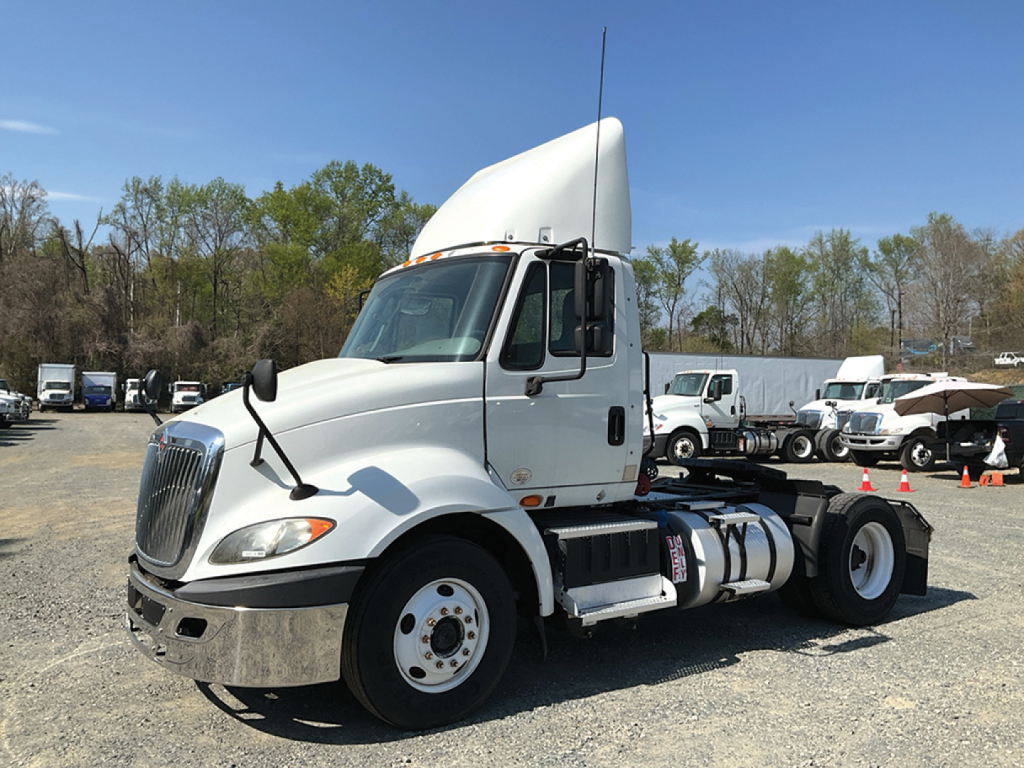 2018 International ProStar+113 conventional daycab truck in a used inventory lot with white cab, fuel tanks, and sleeper area.