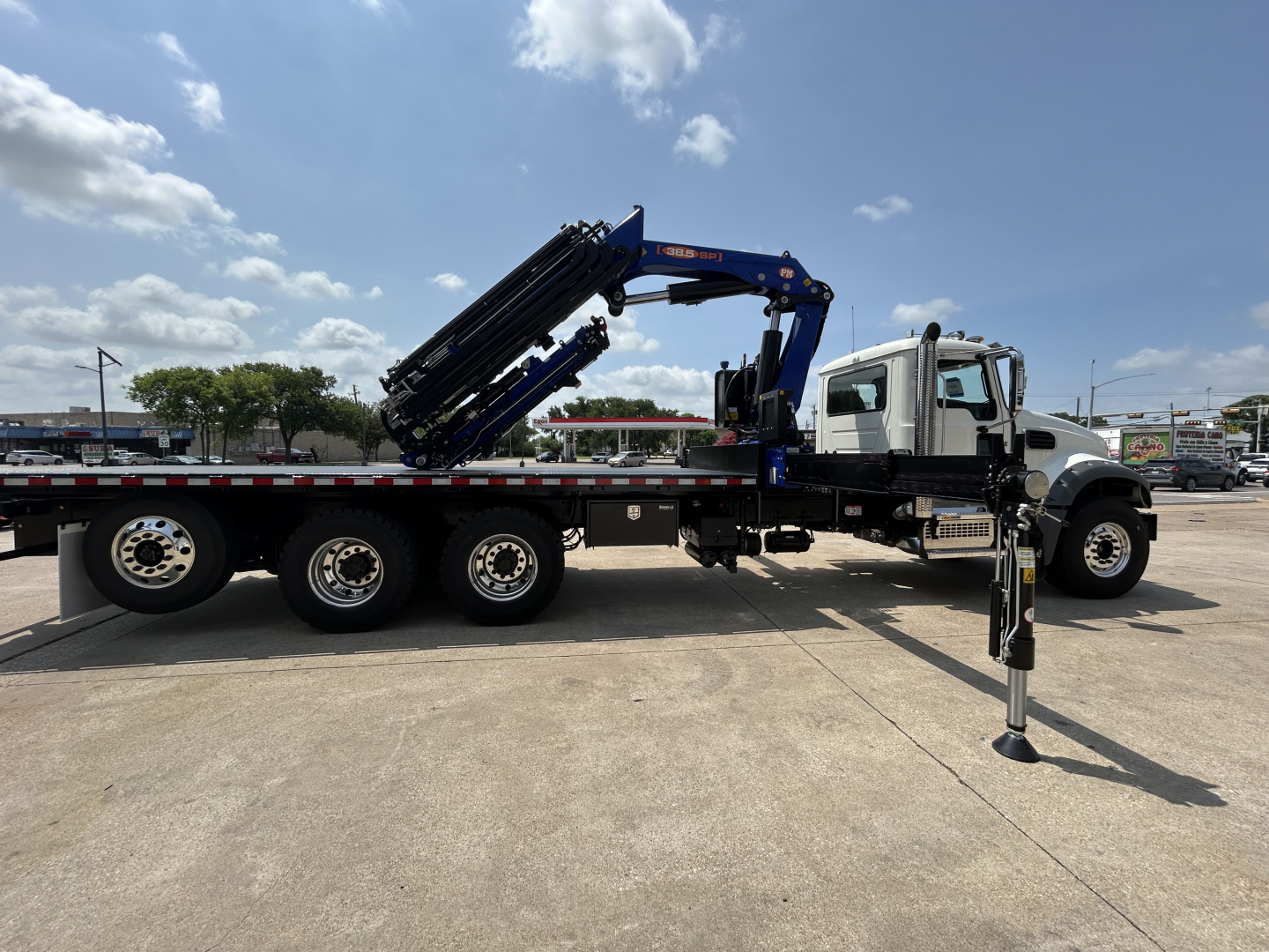 2027 Mack GR64F crane truck on trailer, side view showing extended hydraulic crane and stabilizer.
