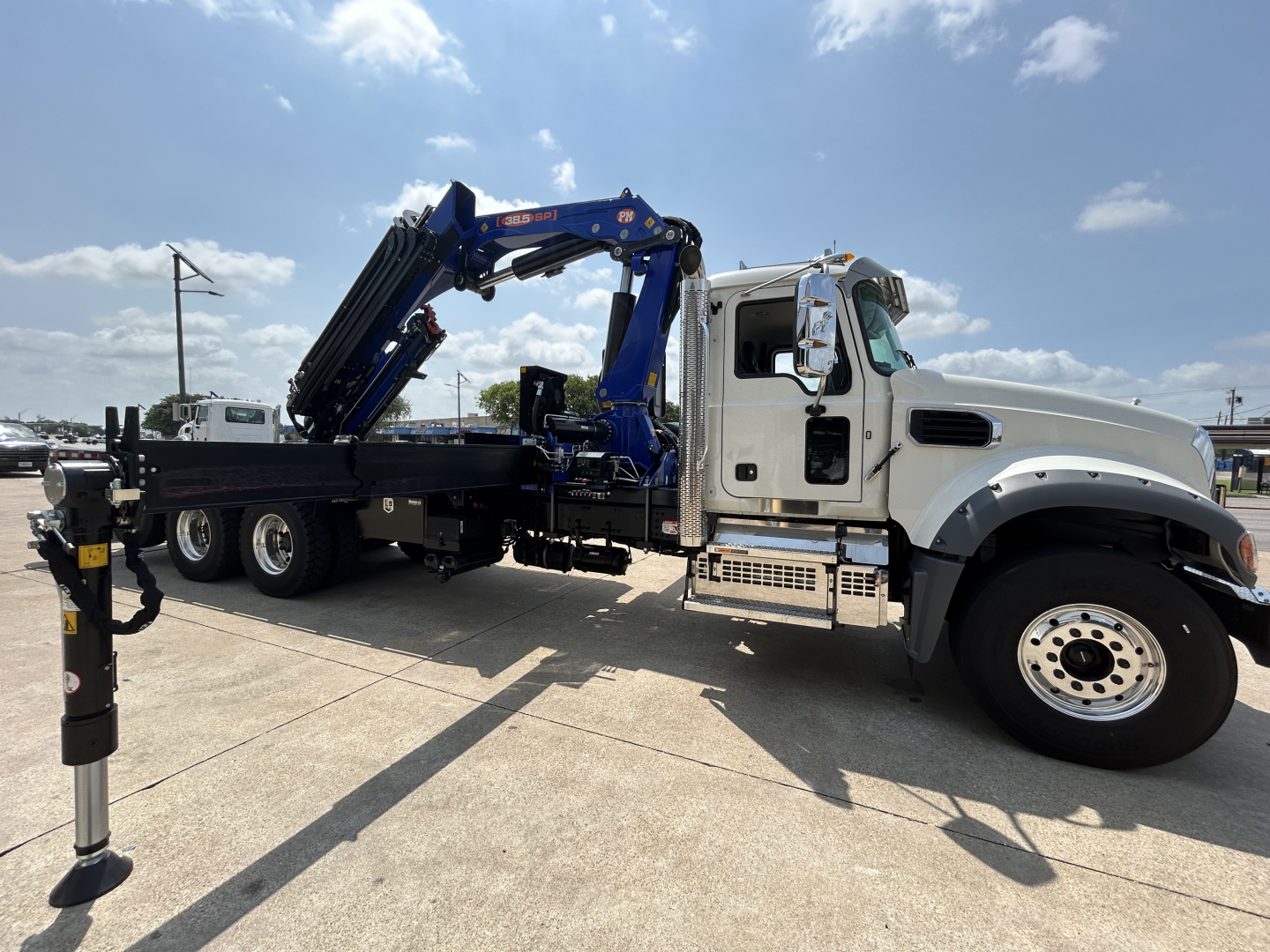 Mack GR64F crane truck in side view showing mounted blue crane on a white cab, with outriggers extended and crane controls visible.