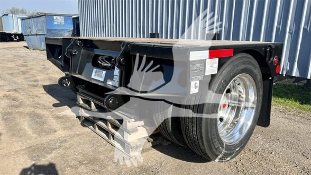 Fontaine Renegade lowboy trailer rear and side view showing flip axle, dual rear tires, black frame, side warning label, and reflective markers.