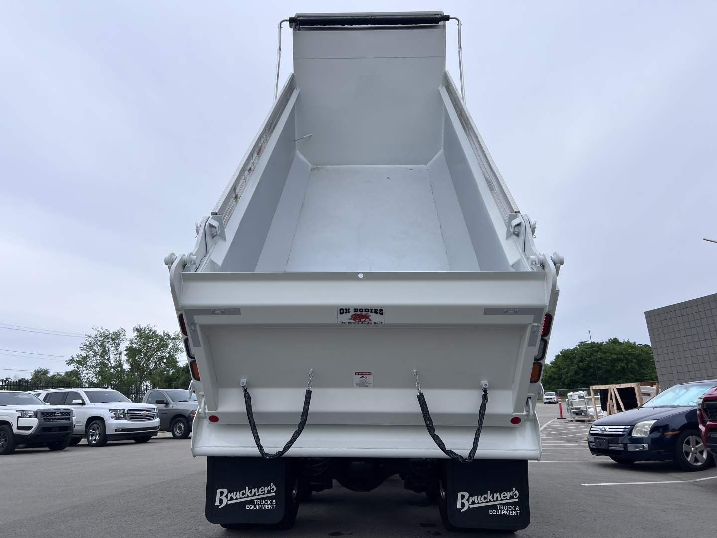 Dump truck bed of a 2027 Mack GR64F with empty dumping cargo area, seen from rear, with Bruckner’s branding on mud flaps.