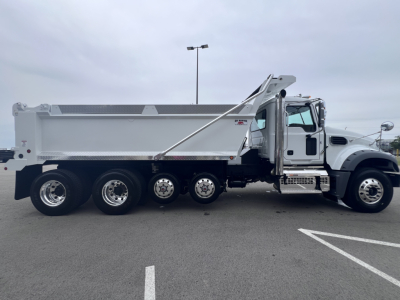 Dump truck side view showing Mack GR64F with dumping bed and chrome wheels.