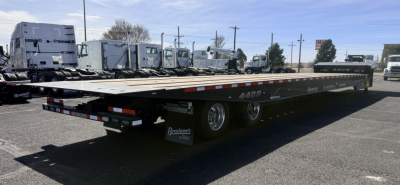 Trailer shows 40 ton Landoll 440B-53 lowboy with long flatbed and triple axle at rear, black frame, white deck edges, reflective tape, and rear taillights.
