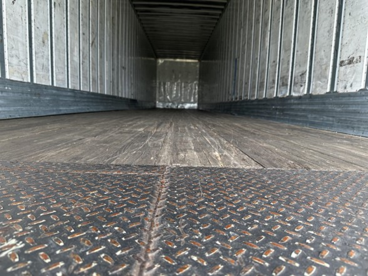 Trailer interior showing metal walls and wooden floor from cargo trailer bed perspective.