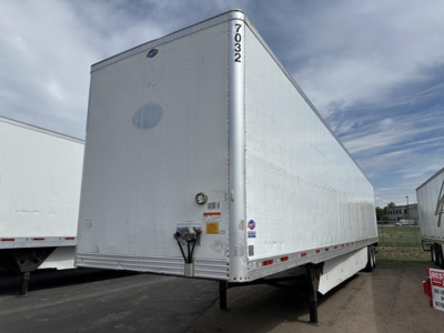 Trailer showing side and rear of a white Utility 4000D-X box trailer with unidentified stickers and VIN tag, front landing gear visible.