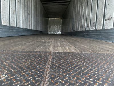 Trailer interior showing metal walls and wooden floor from cargo trailer bed perspective.