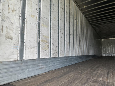 Trailer interior showing metal wall framing and wooden floor inside a box trailer.