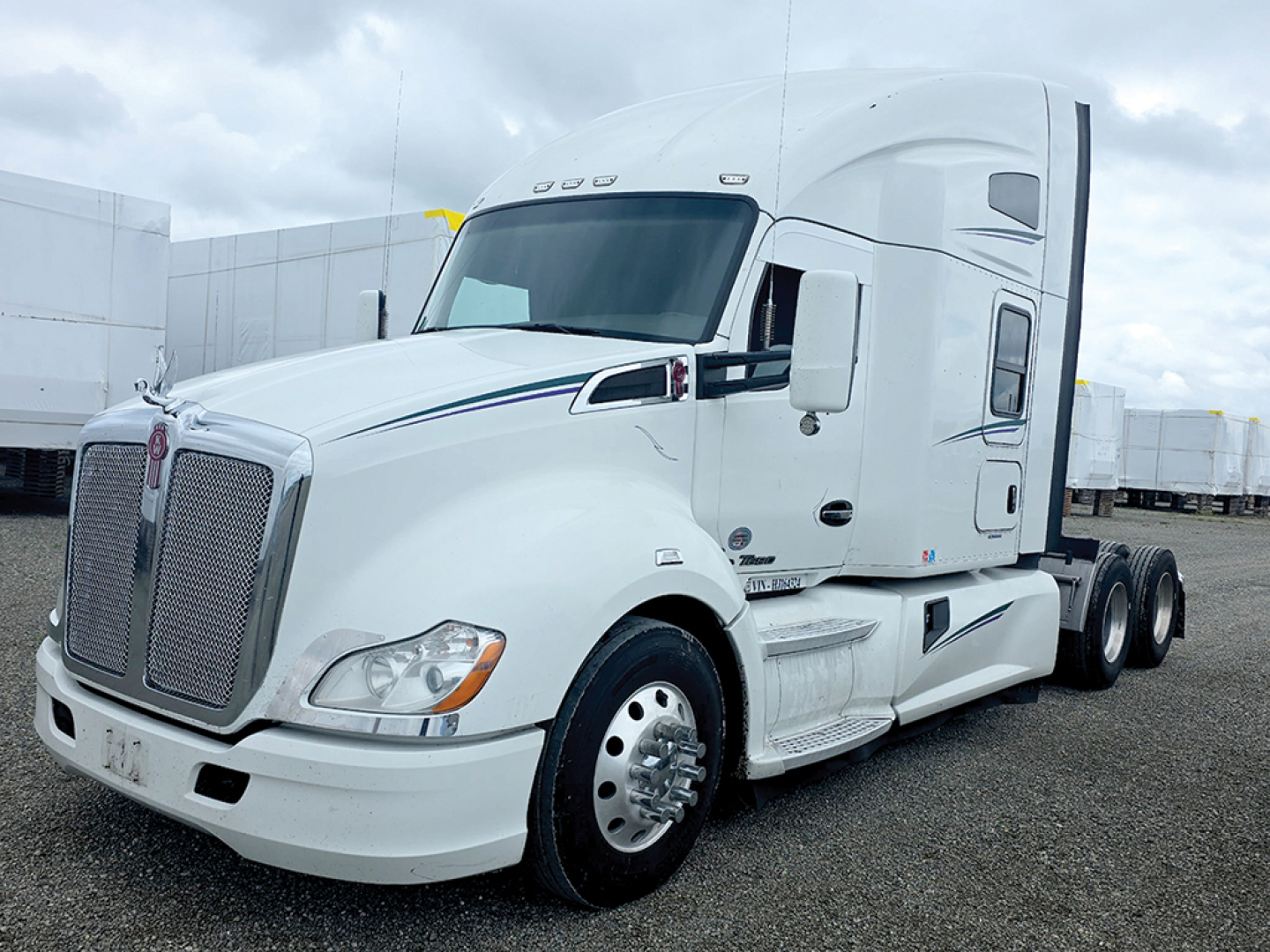 Kenworth T680 tractor, white, sleeper cab, side view with grille and front wheel, showing aerodynamic mirrors and cargo area.