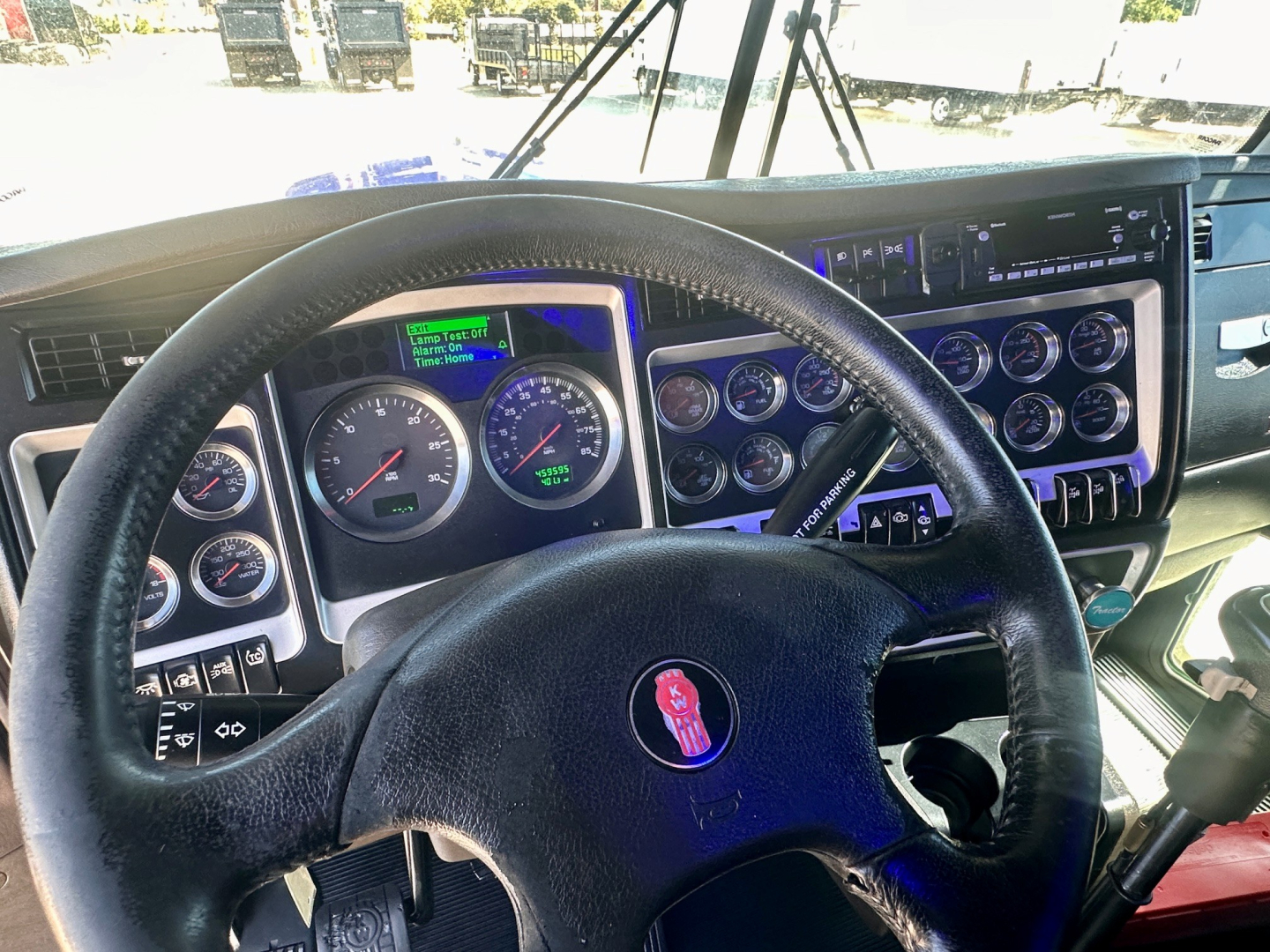 Kenworth W900 dash and steering wheel in cab showing gauges and control panel.