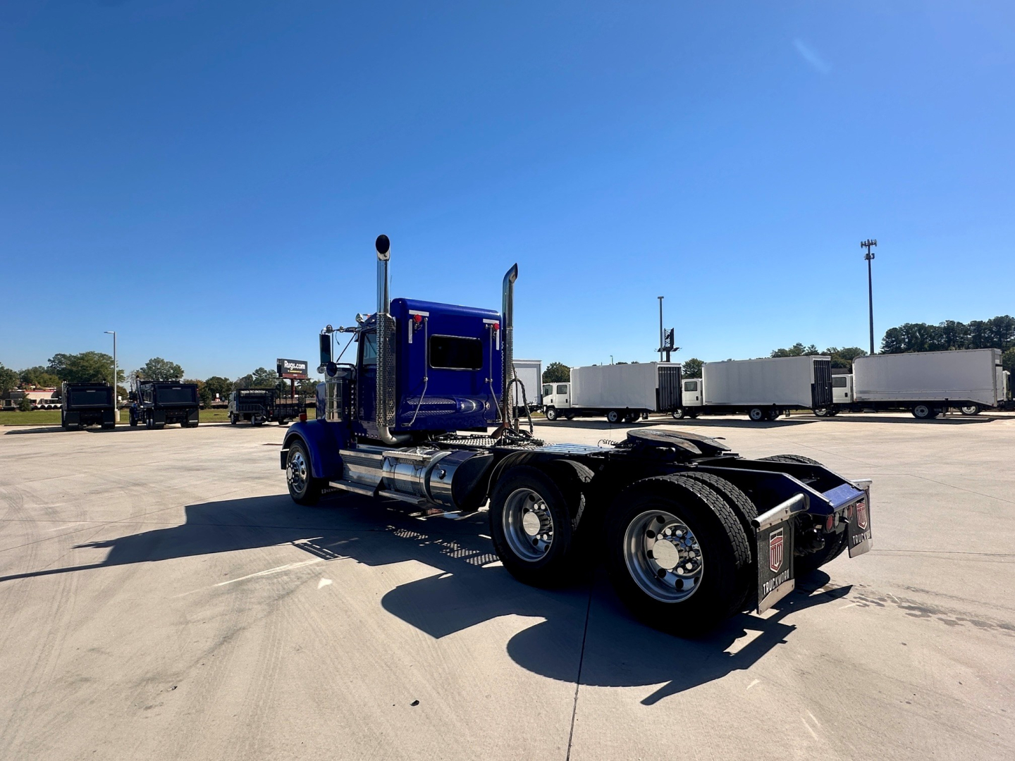 Kenworth W900 truck chassis with blue cab, rear view showing dual rear axles and fuel tanks, VIN 1XKWD49X6MR455849 visible in listing context.