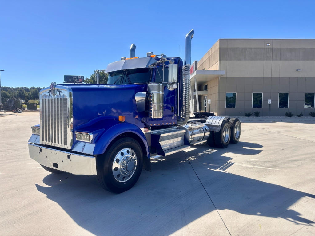 Kenworth W900 tractor in blue, side view, with chrome front grille, dual rear axles, large exhaust stacks and chrome bumper.