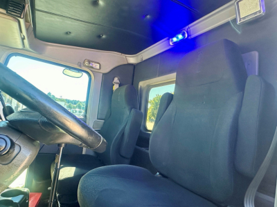 Kenworth W900 cab interior showing steering wheel, driver seat, and blue cab lighting.