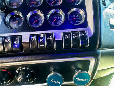 Kenworth W900 dashboard and control panel with multiple gauges and toggle switches in front cabin.