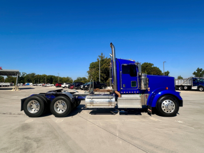 Kenworth W900 conventional daycab truck side view showing dual rear axles, blue exterior, chrome exhaust and fuel tanks, VIN 1XKWD49X6MR455849 visible on listing.
