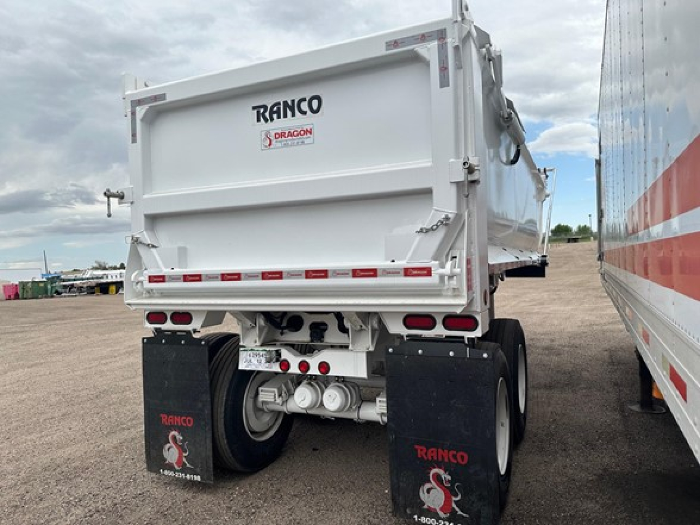 Ranco trailer rear view showing dump bed and dual axles with mud flaps and taillights.