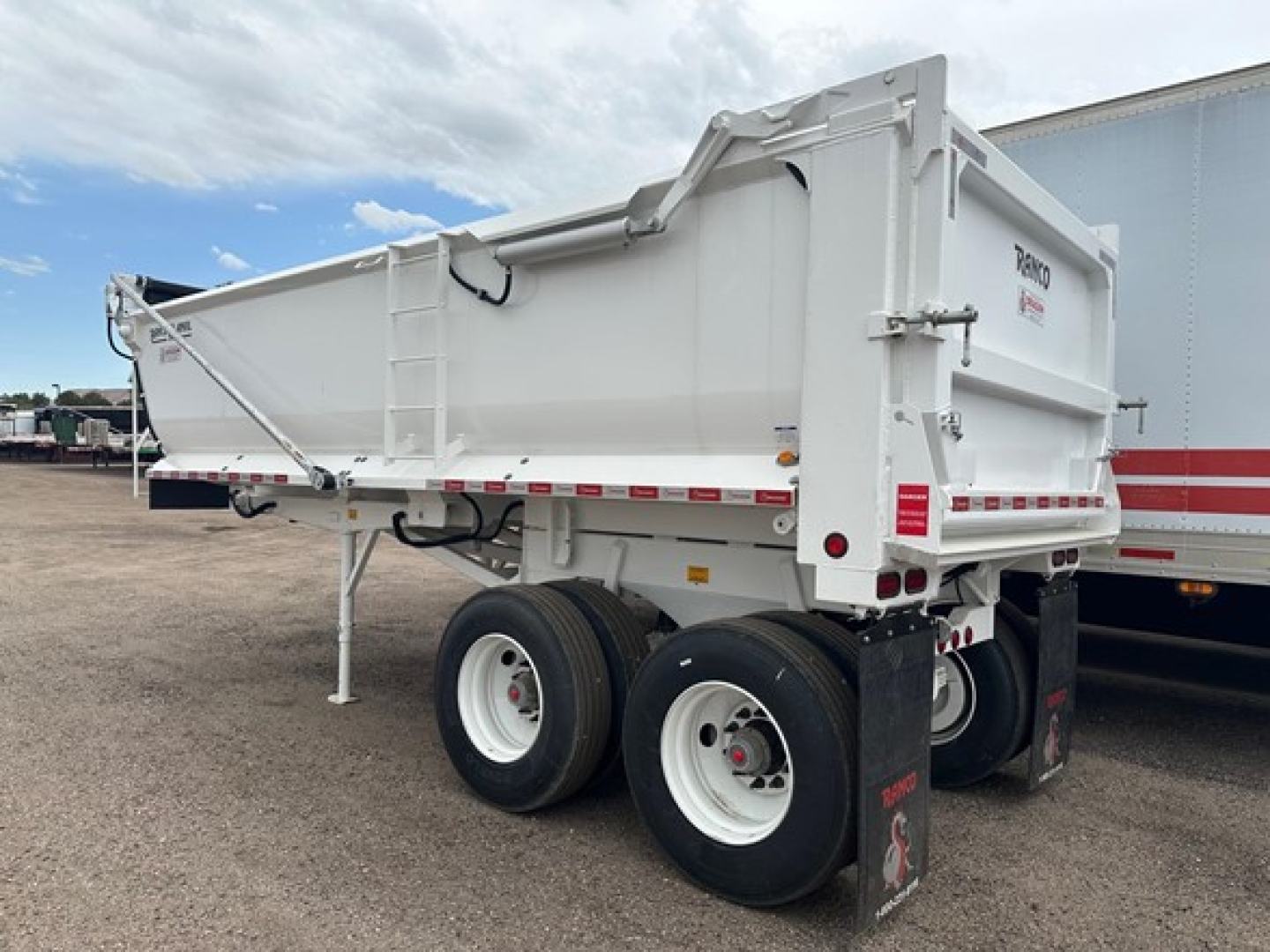 Dump trailer with dual rear axles and white Ranco logo on tailgate showing steel frame and elliptical tub design.
