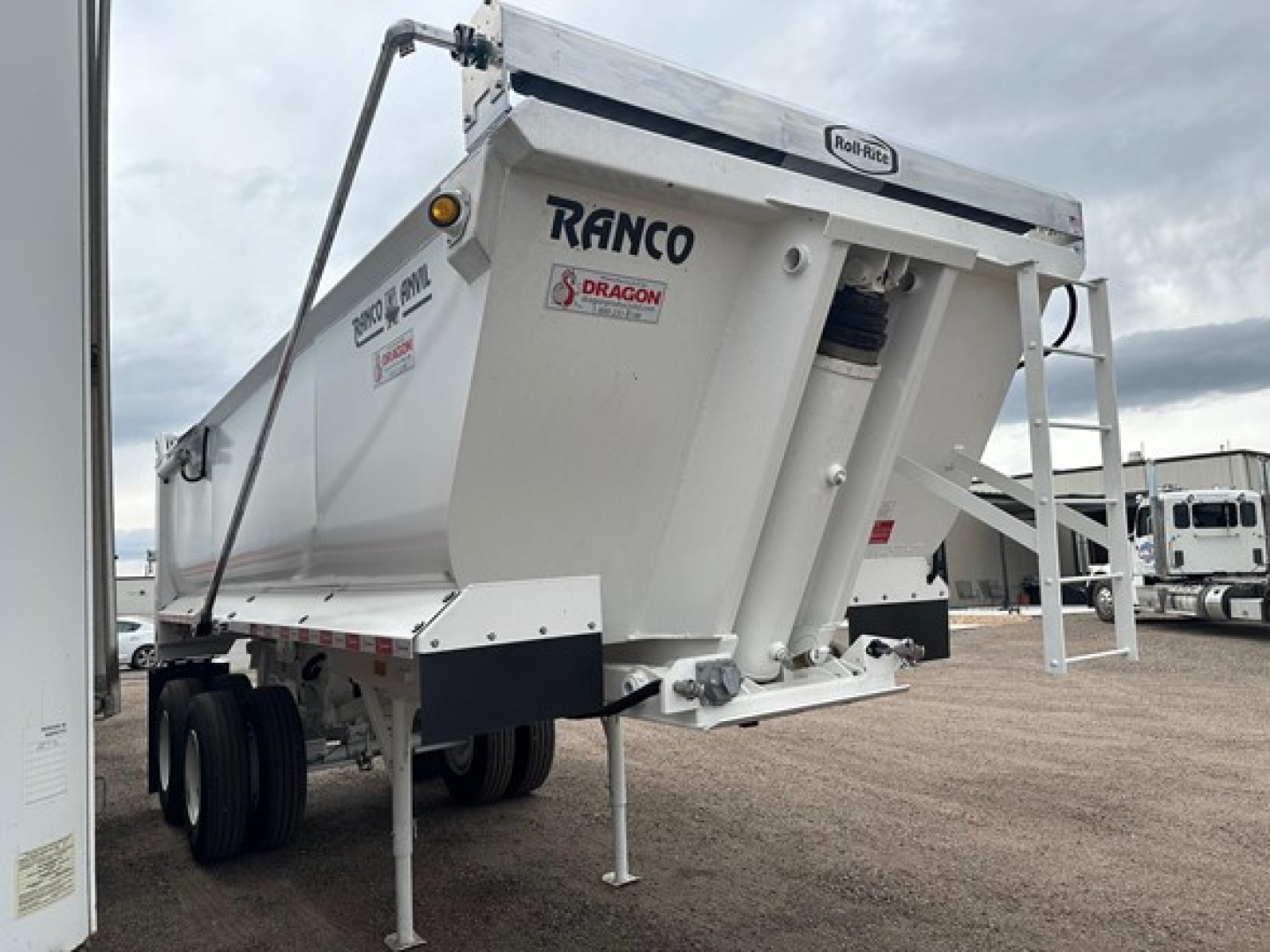 Ranco elliptical tub quarter frame steel rock end dump trailer showing RANCO and Dragon brand decals on white hopper.