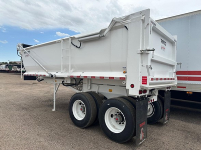 Dump trailer with dual rear axles and white Ranco logo on tailgate showing steel frame and elliptical tub design.