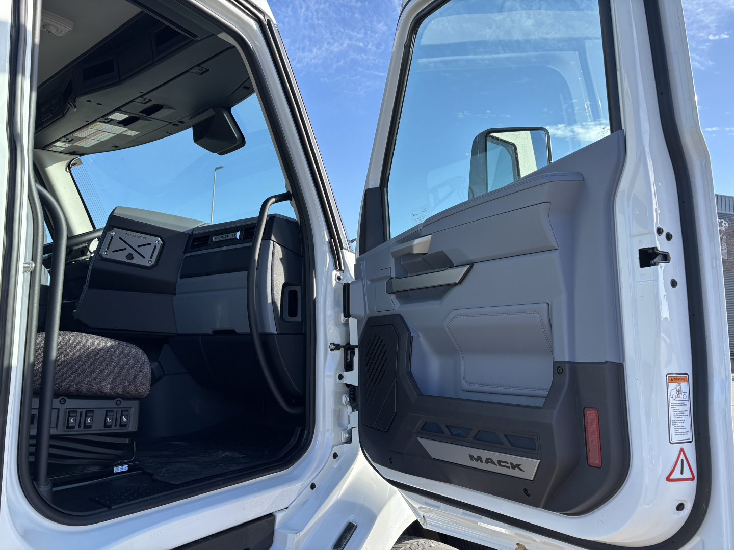 Interior of a Mack AN64T cab with open driver's door, showing dash, steering wheel, and door panel.