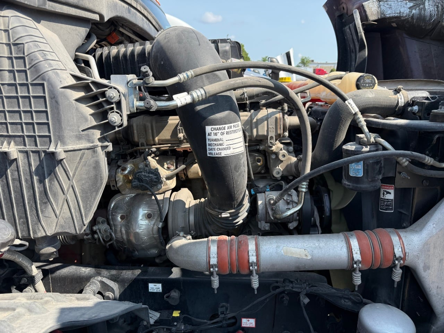 Engine bay of a Freightliner Cascadia with hoses, radiator, and label on a component in view.