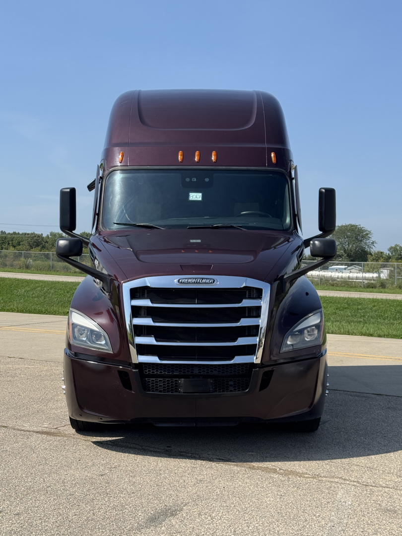 Front view of a maroon 2022 Freightliner Cascadia 126 sleeper tractor showing grille and headlights.