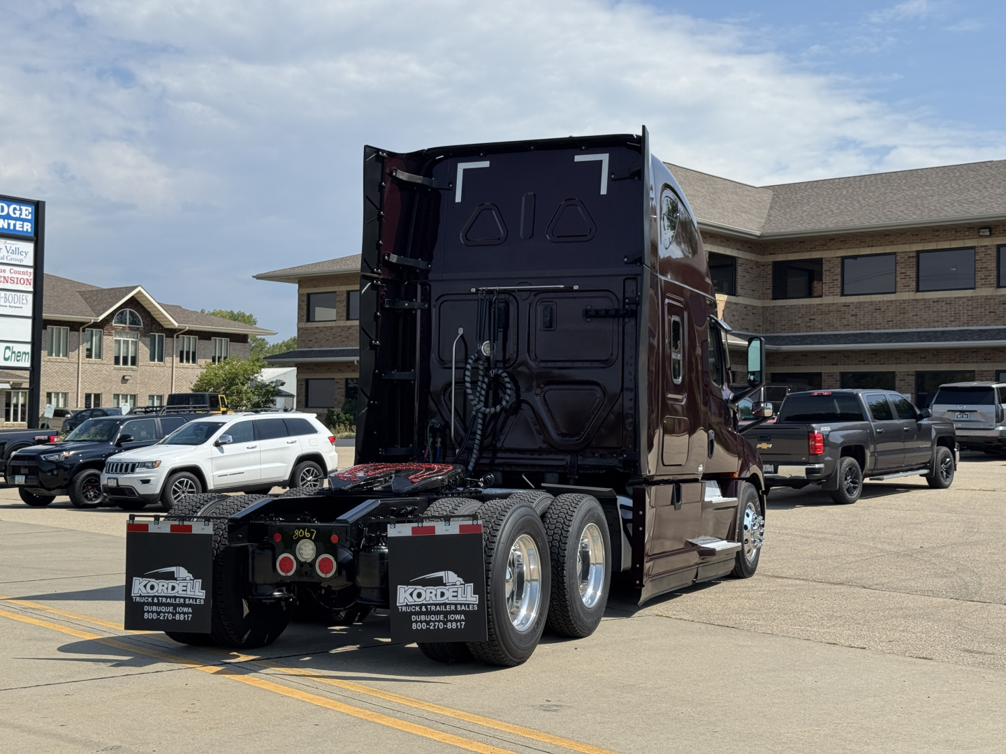 Rear view of a 2022 Freightliner Cascadia 126 semi-truck in a lot showing rear axles and fifth wheel plate.