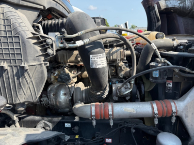 Engine bay of a Freightliner Cascadia with hoses, radiator, and label on a component in view.